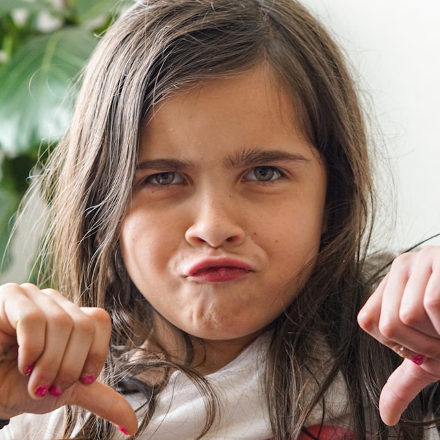 A young girl giving two thumbs down.